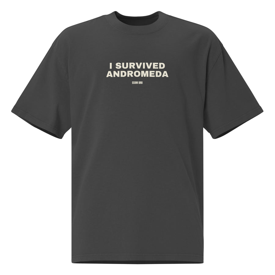 Front supplier mockup of a Faded Black oversized tee with off-white I SURVIVED ANDROMEDA lettering and a small ECOM BRO signature.