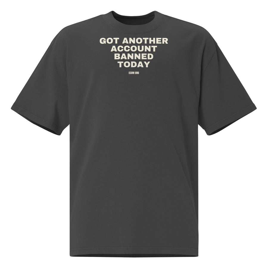 Supplier mockup, front of a Faded Black tee with cream GOT ANOTHER ACCOUNT BANNED TODAY lettering and a small ECOM BRO signature.