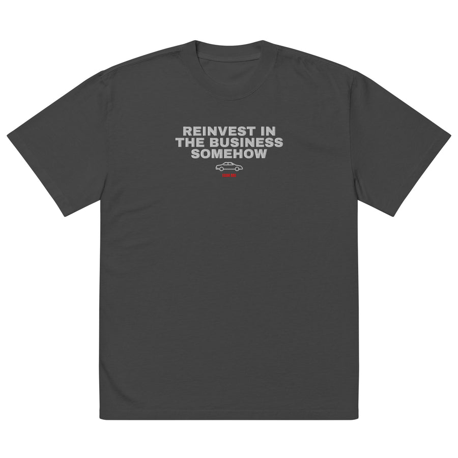 Supplier mockup: front of the Faded Black Reinvest in the Business Somehow embroidered tee, with white headline above a coupe icon and red ECOM BRO signature.