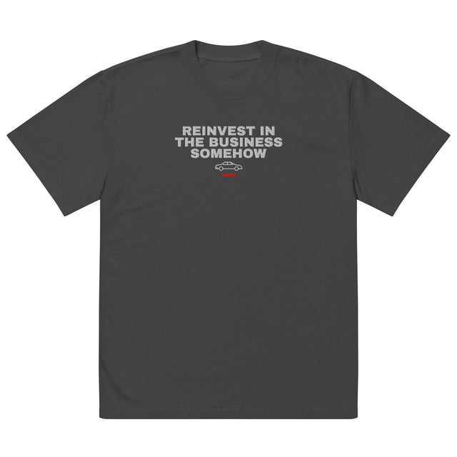 Supplier mockup: front of the Faded Black Reinvest in the Business Somehow embroidered tee, with white headline above a coupe icon and red ECOM BRO signature.