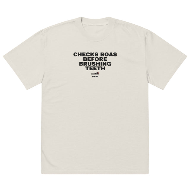 Front supplier mockup of the Faded Bone heavyweight tee with CHECKS ROAS BEFORE BRUSHING TEETH lettering above a toothbrush chart and ECOM BRO signature.